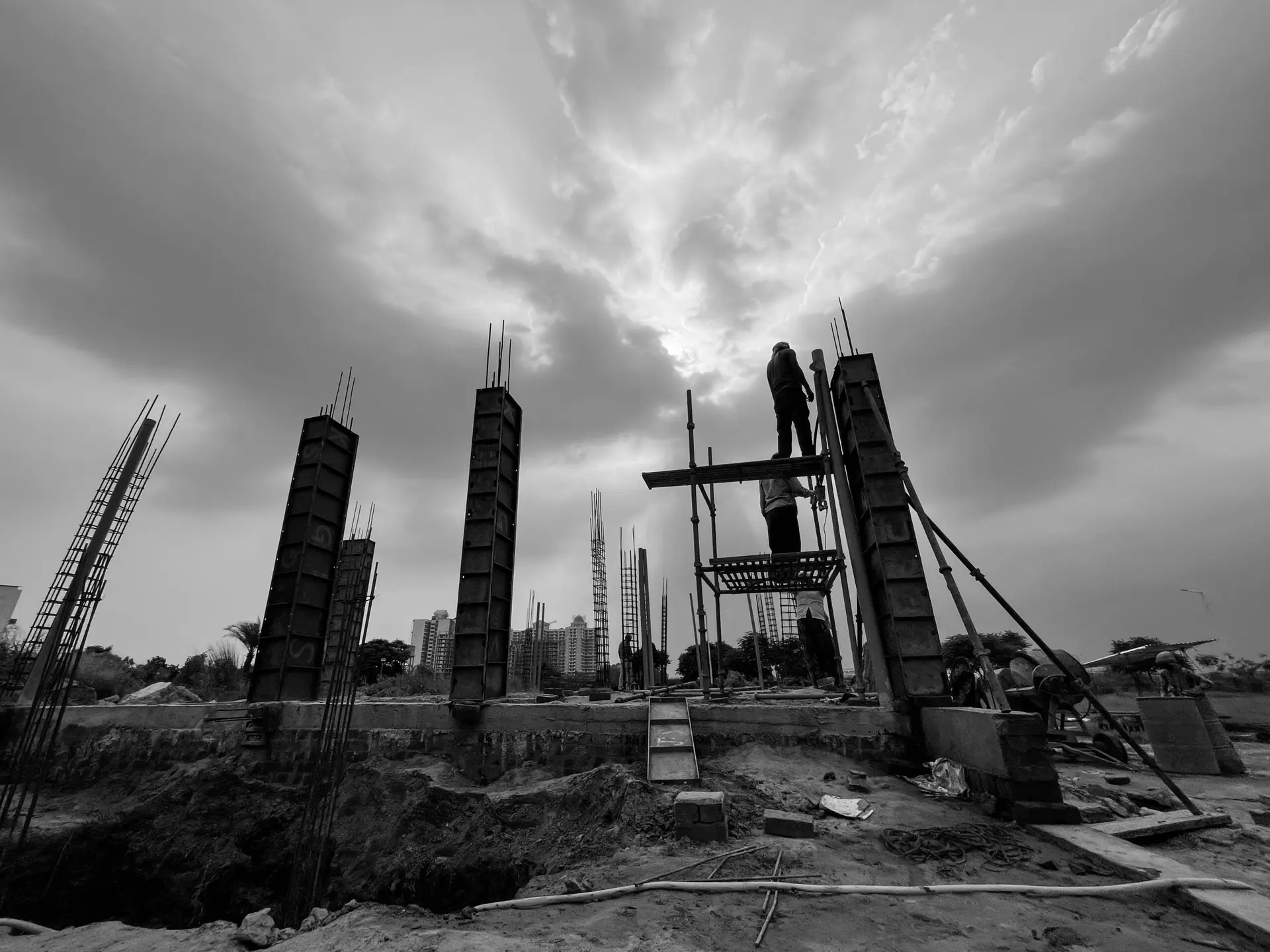 Black and white image capturing construction workers at a building site in Rasulpur, India.