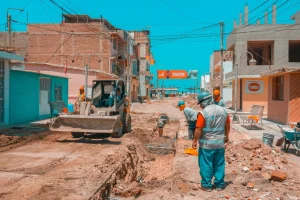 Workers engage in road construction under clear blue skies in a city street.